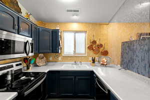 Kitchen featuring stainless steel appliances, light countertops, and a textured ceiling