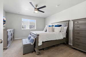 Bedroom with a ceiling fan and light colored carpet