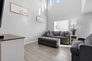 Living area with light wood-style flooring and a towering ceiling