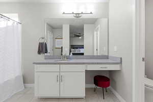Full bathroom with vanity, ceiling fan, light tile patterned floors, and connected bathroom