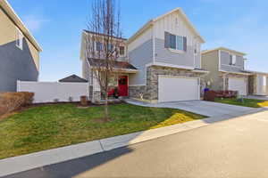 View of front of house with board and batten siding, stone siding, a garage, and concrete driveway