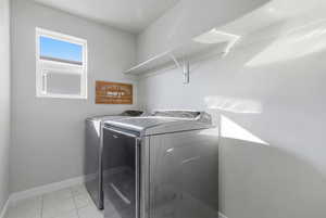 Washroom with light tile patterned floors and washer and clothes dryer