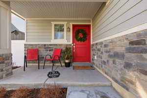 Property entrance featuring stone siding and a porch