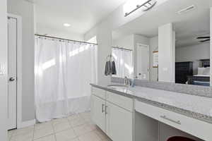 Bathroom with vanity, light tile patterned flooring, shower / bathtub combination with curtain, connected bathroom, and ceiling fan