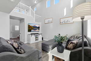Living area featuring wood finished floors, a high ceiling, and stairway