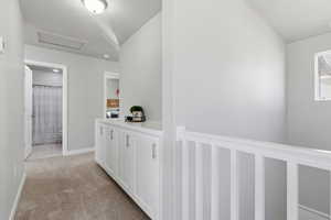 Hallway featuring light carpet and attic access