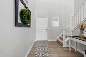 Entrance foyer featuring stairs, light wood-style flooring, and a towering ceiling