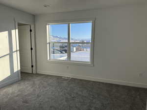 Spare room featuring a mountain view, dark colored carpet, and a textured ceiling