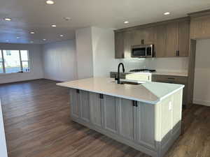 Kitchen featuring an island with sink, light stone counters, stainless steel appliances, recessed lighting, and tasteful backsplash