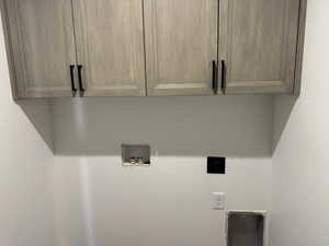 Washroom with hookup for a washing machine, cabinet space, and hookup for an electric dryer