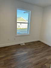 Unfurnished room with dark wood-style flooring and baseboards
