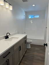Full bath with vanity, dark wood-type flooring, and bathing tub / shower combination