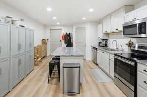 Kitchen featuring stainless steel appliances, light stone countertops, a kitchen island, recessed lighting, and a breakfast bar area
