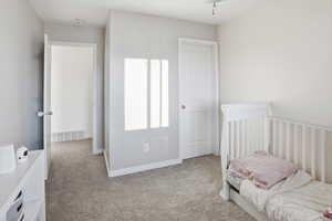 Carpeted bedroom featuring a crib and baseboards