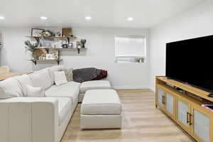 Living room with light wood-type flooring and recessed lighting