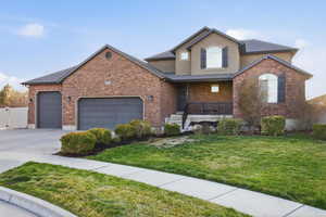 Traditional home with a porch, a front yard, an attached garage, concrete driveway, and stucco siding