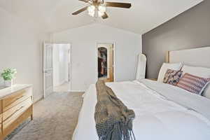 Bedroom featuring vaulted ceiling, a spacious closet, light carpet, and a ceiling fan