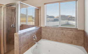 Full bath with a jetted tub, plenty of natural light, and a stall shower