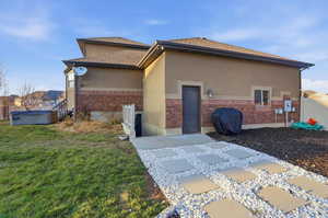 View of property exterior featuring a hot tub, stucco siding, and brick siding