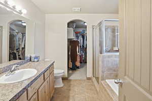 Bathroom featuring a spacious closet, vanity, light tile patterned flooring, and a shower stall