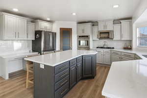Kitchen featuring decorative backsplash, stainless steel appliances, light stone counters, and recessed lighting