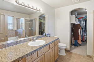 Bathroom with a spacious closet, a stall shower, a bath, vanity, and dark tile patterned flooring
