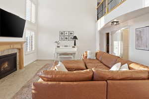 Carpeted living area with a towering ceiling, a glass covered fireplace, and arched walkways