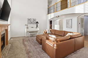 Living room with a tile fireplace, a towering ceiling, healthy amount of natural light, and arched walkways