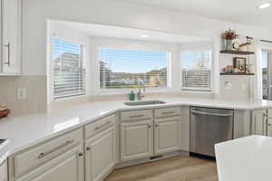 Kitchen featuring dishwasher, light stone counters, white cabinets, backsplash, and recessed lighting