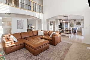 Living room with a chandelier, arched walkways, a high ceiling, and light carpet