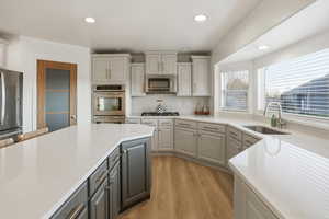 Kitchen featuring gray cabinetry, light stone countertops, light wood-style floors, appliances with stainless steel finishes, and recessed lighting