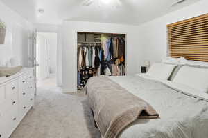 Bedroom featuring light carpet, a ceiling fan, and a closet