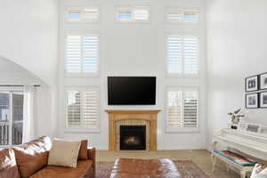 Living area with a high ceiling, a fireplace, carpet flooring, arched walkways, and plenty of natural light