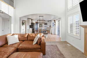 Living area with arched walkways, a towering ceiling, plenty of natural light, and light colored carpet