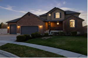 Traditional-style house with a porch, an attached garage, a front lawn, concrete driveway, and stucco siding