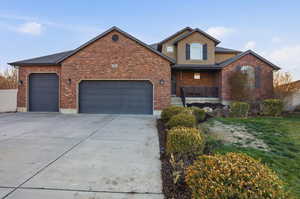 View of front facade featuring a porch, driveway, an attached garage, a front lawn, and brick siding