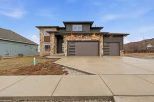 Prairie-style house featuring stone siding and driveway