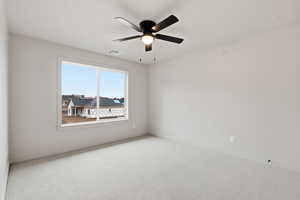 Carpeted spare room featuring a ceiling fan and baseboards