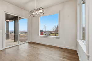Unfurnished dining area with a chandelier and wood finished floors