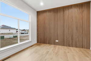 Spare room featuring wood walls, wood finished floors, and an accent wall