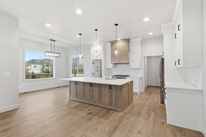 Kitchen with backsplash, a kitchen island with sink, hanging light fixtures, white cabinets, and recessed lighting