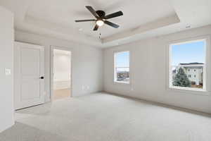 Unfurnished room with a raised ceiling, light carpet, and ceiling fan