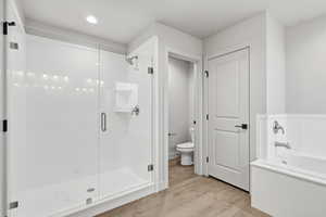 Bathroom with a stall shower, light wood finished floors, and a bath