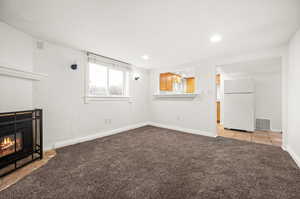 Unfurnished living room with light colored carpet and a fireplace with flush hearth
