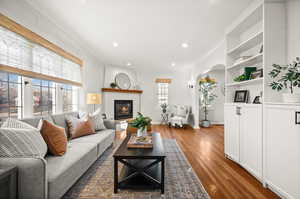 Living area featuring arched walkways, a fireplace, dark wood-style flooring, recessed lighting, and built in features