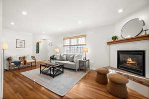 Living area with arched walkways, a glass covered fireplace, recessed lighting, and hardwood / wood-style flooring