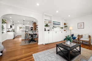 Living room with arched walkways, light wood-type flooring, and recessed lighting