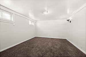 Basement with dark colored carpet and baseboards