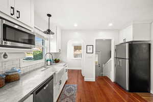Kitchen featuring appliances with stainless steel finishes, white cabinetry, light stone counters, plenty of natural light, and recessed lighting