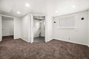 Unfurnished bedroom with dark carpet and ensuite bathroom